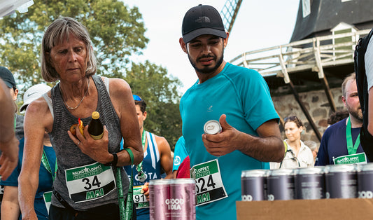 En kvinna och en man på Malmöloppet står och plockar Good Idea bubbelvatten från Good Idea ståndet