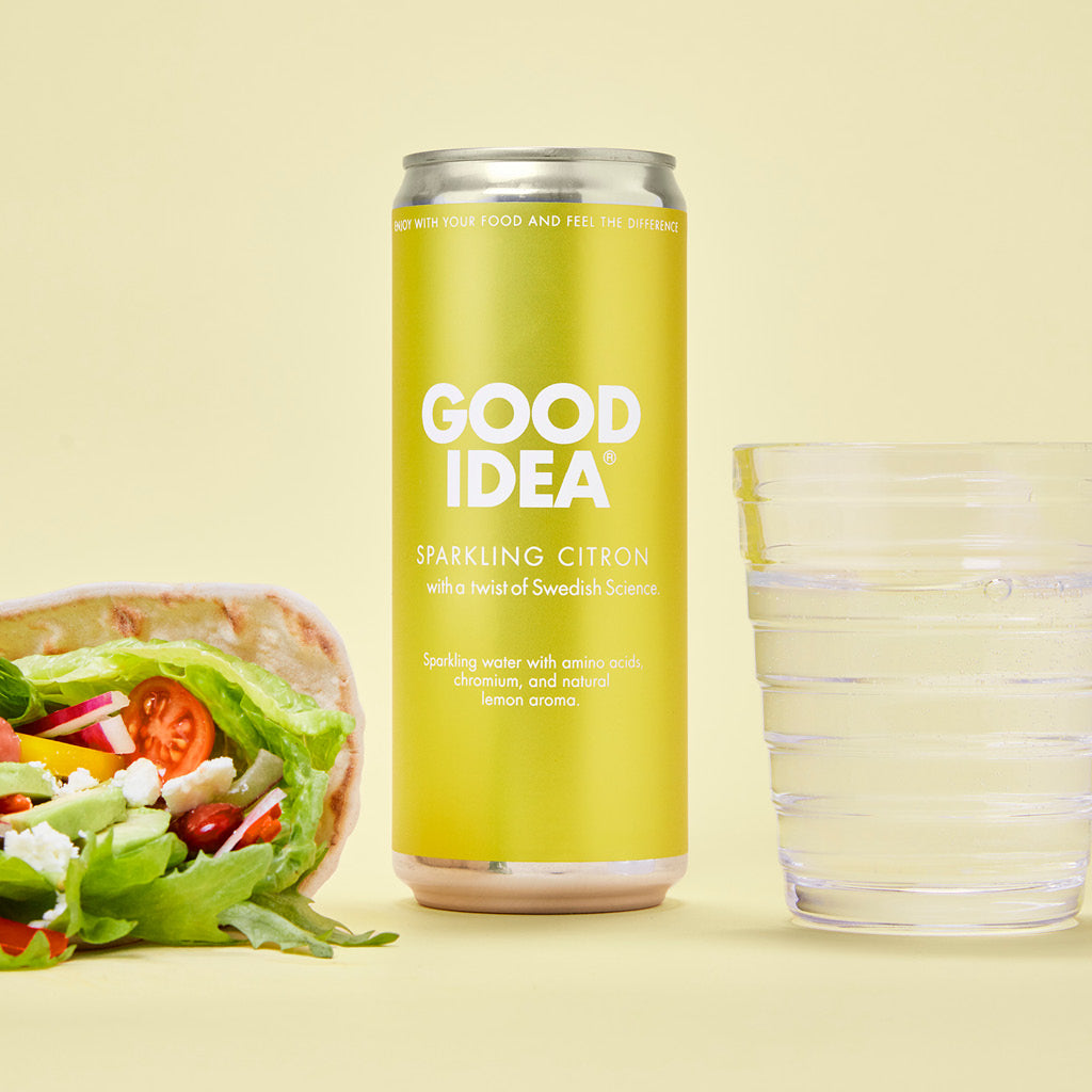 Till vänster en wrap med grönsaker, i mitten en burk av den blodsocker balanserande måltidsdrycken Good Idea Sparkling Citron, till höger ett dricksglas med bubbelvatten, mot en gul bakgrund.
